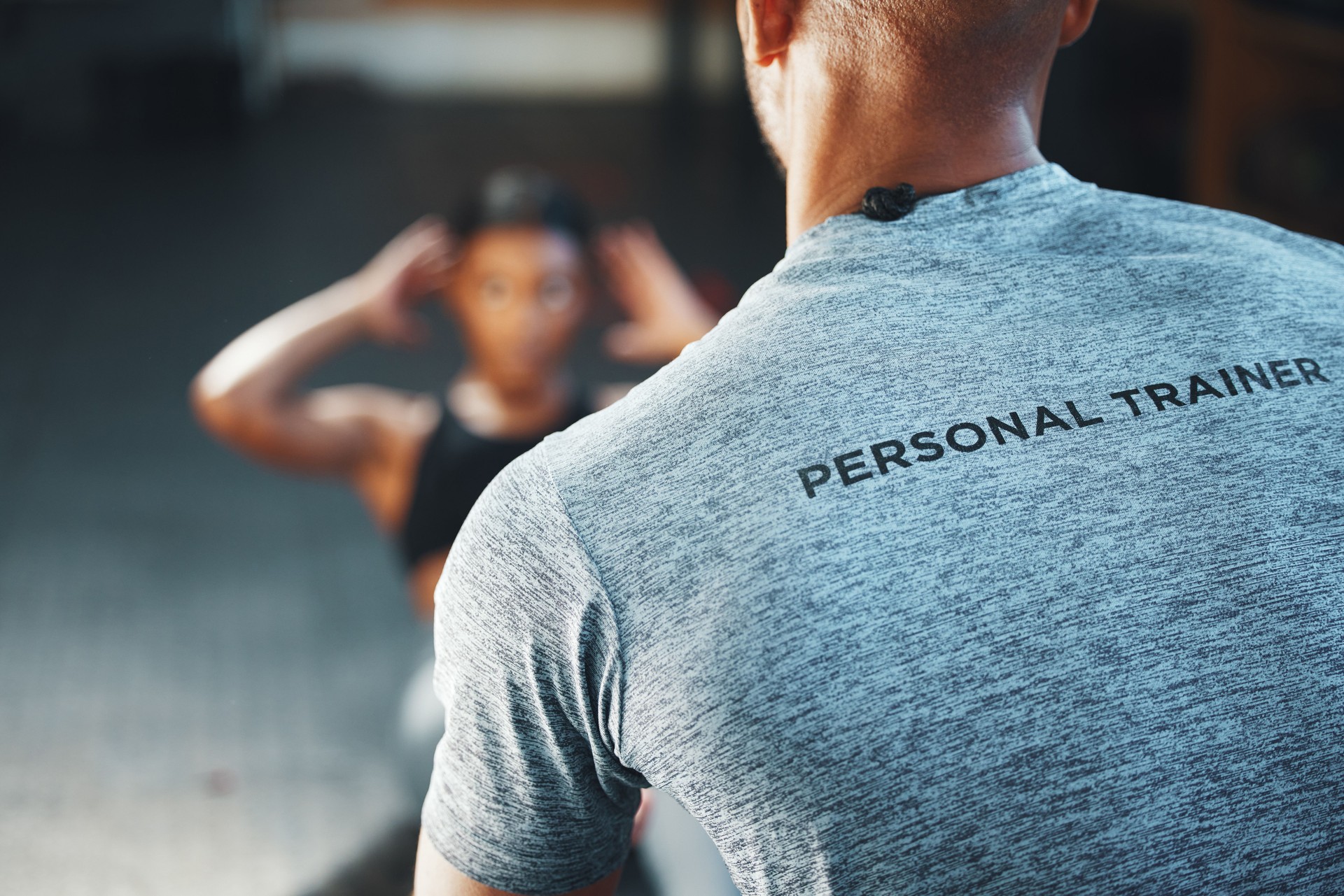 Closeup shot of a personal trainer assisting a client in a gym
